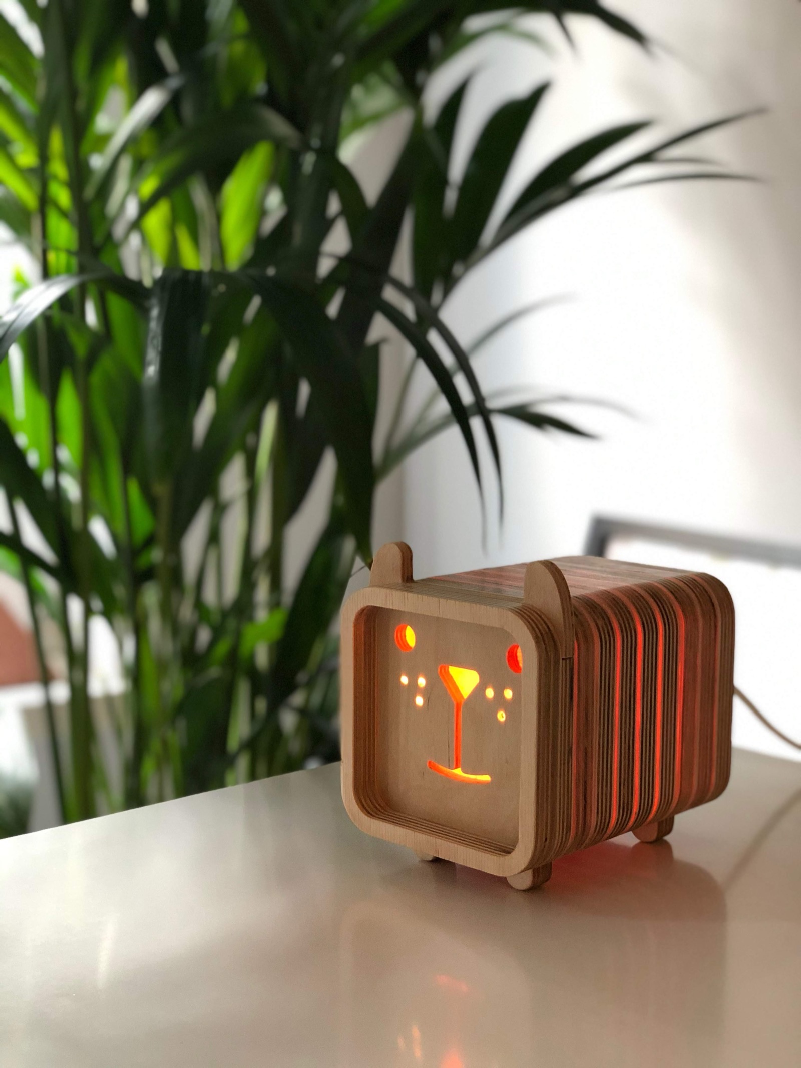 A bear-eared Lampun night light glowing warm orange on a desk, a martini-glass face cut into the front panel